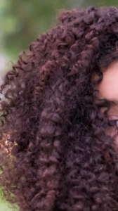 Deep burgundy red curly hair.